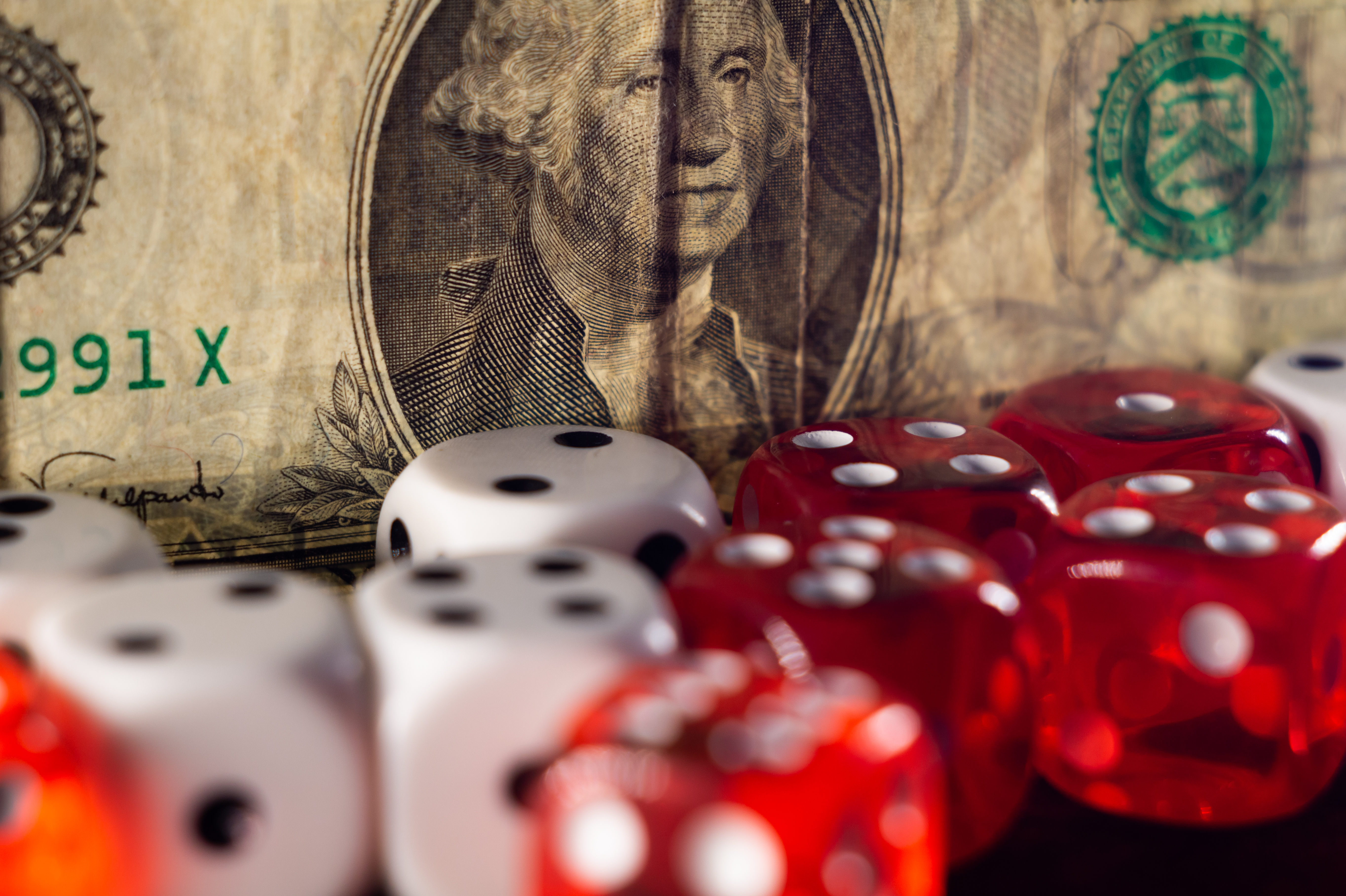 Closeup shot of a pile of dice in front of a dollar bill- gambling, casino concept