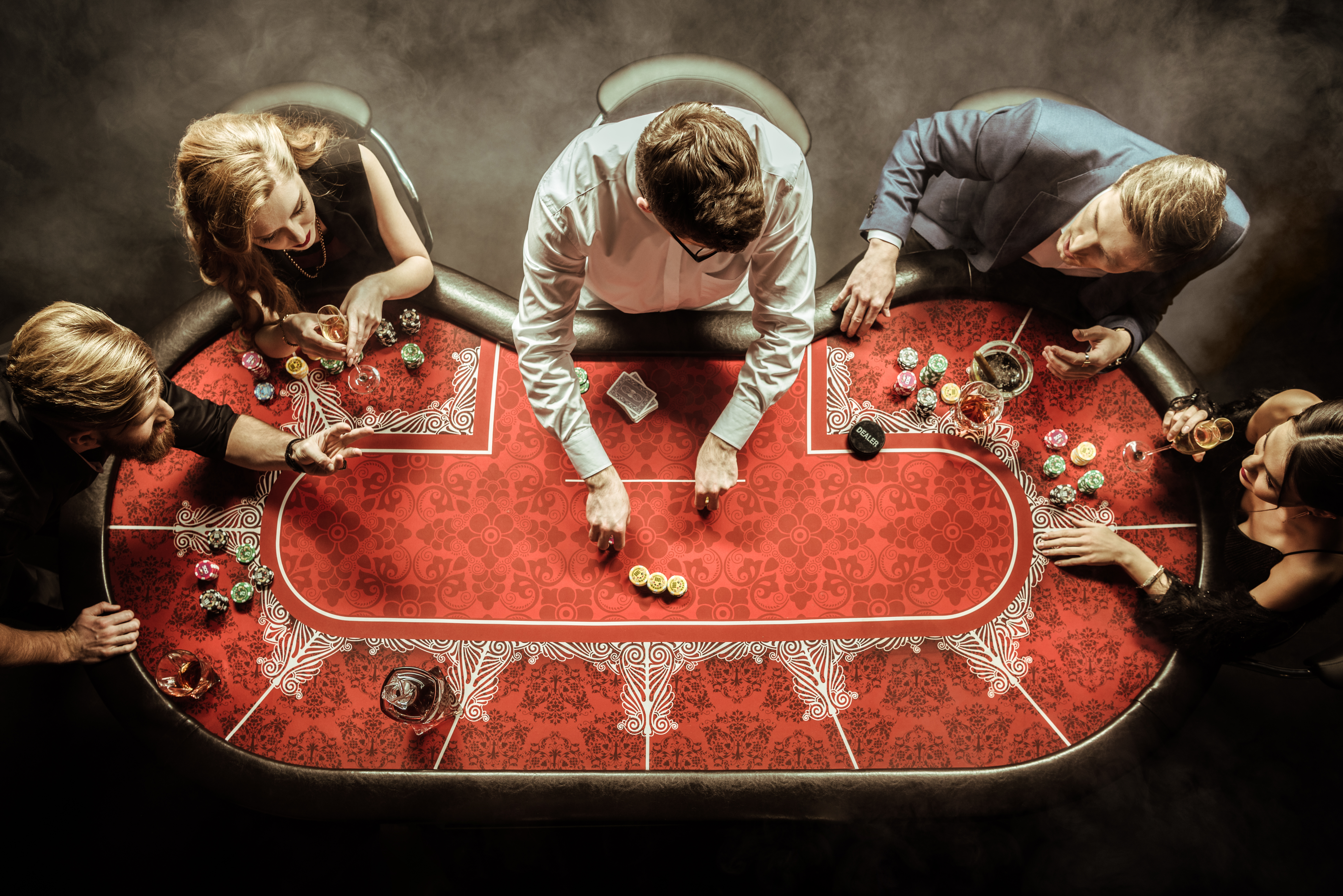 top view of men and women playing poker in casino